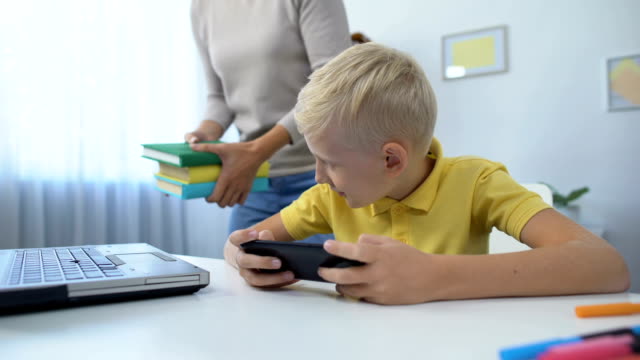 Süchtige-Junge-spielen-Handy-Spiel-statt-Hausaufgaben-zu-tun,-Mama-schimpft-Sohn