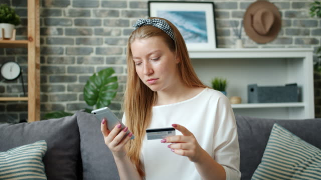Slow-motion-of-teenager-paying-online-with-bank-card-using-smartphone-at-home