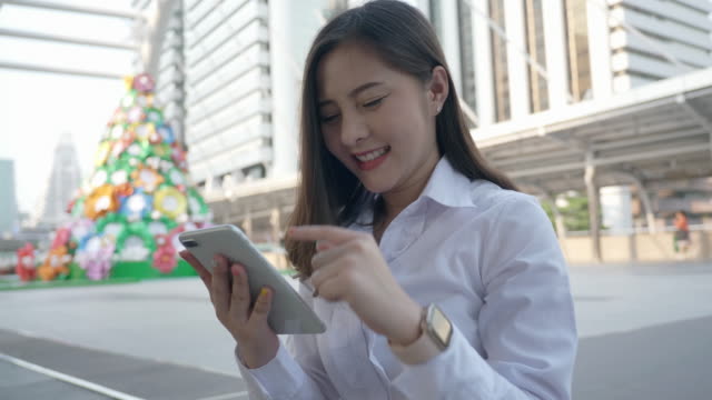 Excited-business-asian-woman-celebrating-good-news-checking-smart-phone-in-the-modern-city-center-in-the-evening-of-Bangkok-Thailand.-Concept-Technology-communication,-success-by-mobile-phone