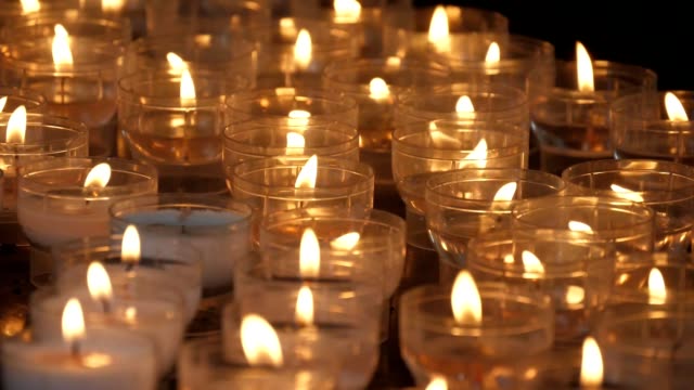 Inspirierender-Blick-auf-viele-Kerzen-im-Freien,-die-in-einer-katholischen-christlichen-Kirche-in-Belgien-in-Zeitlupe-angezündet-wurden.-Sie-sehen-religiös-und-wunderschön-aus.