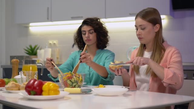 Beautiful-woman-serving-salad-to-female-friend,-women-having-breakfast-together