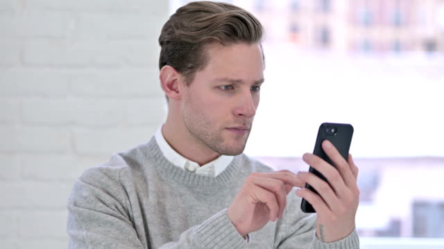 The-Portrait-of-Relaxed-Creative-Young-Man-using-Smartphone