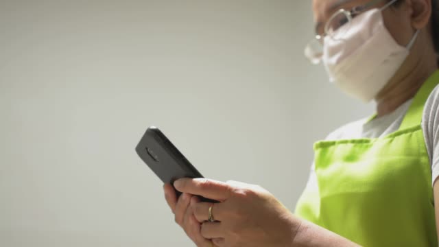 Hausfrau-trägt-Schutzmaske-SMS-Nachricht-auf-handy-für-die-Kommunikation-und-Chatten-auf-Social-Online-zu-Hause.-Datenverfolgung-und-tägliche-Nachrichten-mit-Demhandy.