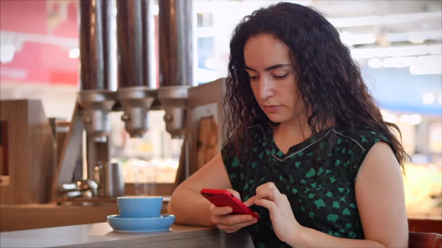 Girl-is-typing-on-the-smartphone-while-sitting-in-a-cafe.-Close-up-portrait-of-happy-pretty-young-woman,-girl-sitting-in-a-cafe-drinking-morning-coffee-in-the-city.