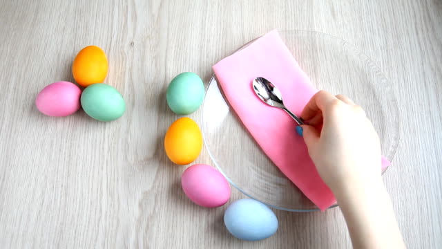Hand-takes-a-teaspoon-from-the-table.-On-the-table-are-colored-easter-eggs.