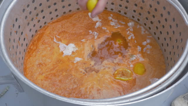 Mann-drückt-Zitronen-in-einen-großen-Topf-würzige-Cajun-Brühe-auf-Langusten-Kochen