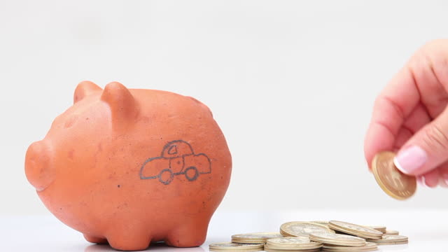 Woman-saving-money-into-a-traditional-clay-piggy-bank-for-a-car