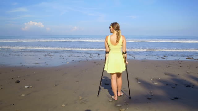 CLOSE-UP-starke-Frau-mit-Krücken-lächelnd-in-den-Sommerferien-am-tropischen-Strand