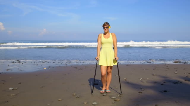 CLOSE-UP-weiblich-mit-Krücken-und-gute-Krankenversicherung-auf-Strandurlaub