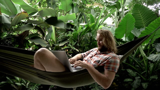 Сryptocurrency-trader-making-bargain-on-laptop-while-lying-on-hammock