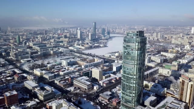 Vista-aérea-del-rascacielos-está-en-el-centro-de-la-ciudad-en-invierno,-cielo-azul-cielo-y-los-tejados-nevados-de-fondo-edificios