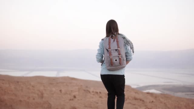 Woman-takes-photos-of-montain-scenery.-Slow-motion.-Casual-traveler-girl-with-backpack-using-smartphone.-Israel-Dead-Sea