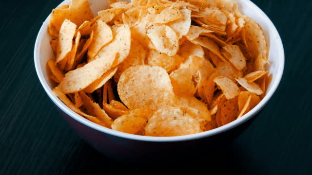 Large-plate-with-potato-chips-on-the-table.-Female-hands-with-beautiful-manicure-take-chips