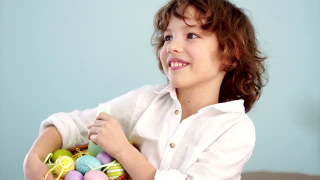 Studio-portrait-of-a-merry-boy-with-an-Easter-basket-in-his-hands.-Red-haired,-curly-blue-eyed-child
