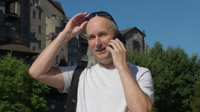 Mann-in-Sonnenbrillen-aufrufen-und-im-Gespräch-per-Telefon-in-Stadt