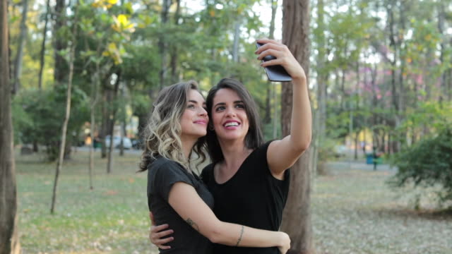 Pareja-de-novias-LGBT-lesbianas-tomando-un-selfie-junto-a-teléfono-móvil-en-el-Parque