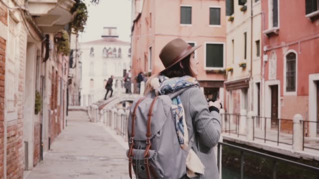 Glücklich-schönen-touristischen-Mädchen-fotografieren-Smartphone-zu-Fuß-in-der-erstaunlichen-Wasserkanal-Straße-in-Venedig-Italien-Slow-Motion.