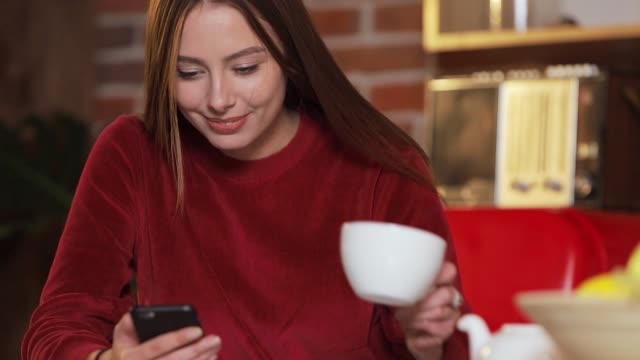 Mujer-joven-navegando-por-internet,-revisar-novedades-en-redes-sociales-durante-el-uso-de-smartphone-en-la-cocina.
