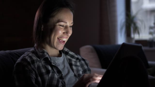Mujer-feliz-con-tableta-digital-en-la-noche