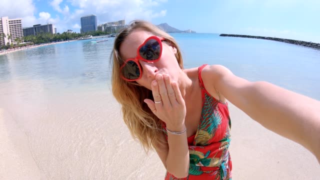 Selfie-of-girl-with-heart-shaped-sunglasses-on-beach-in-Hawaii.-Young-woman-taking-a-selfie-on-Waikiki-Beach-in-Honolulu.-Hawaii-USA