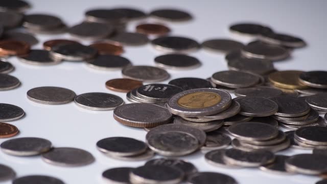 close-up-motion-footage-of-money-coins-falling-to-pile-of-coins-on-white-floor.-business,-financial-for-money-saving-or-investment-concept