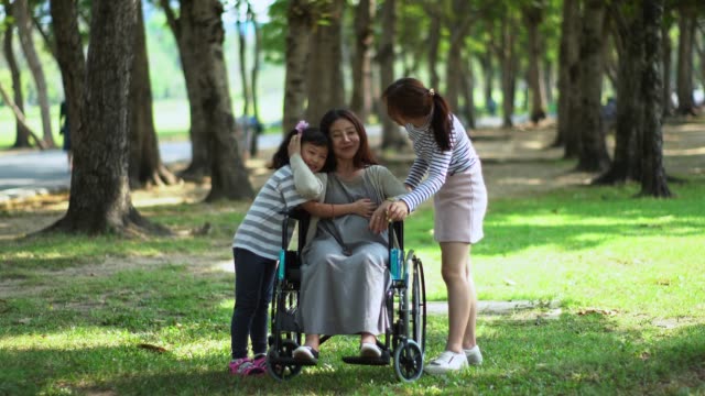 Mutter-auf-Rollstuhl-und-zwei-liebenswerte-Tochter-im-Park