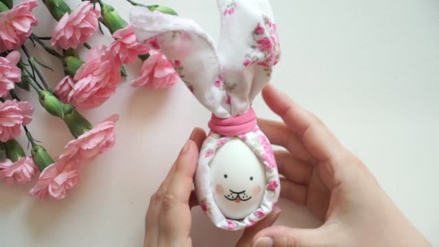 Women's-hands-holds-chicken-egg-decorated-for-Easter-bunny-in-hands.