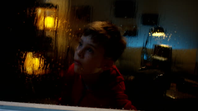 Rolltscholregen-Junge-beobachtet-Sturm-aus-dem-Zimmer