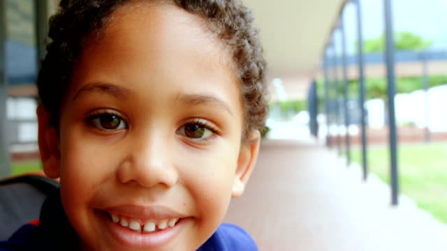 Close-up-of-happy-disabled-African-American-schoolboy-sitting-on-wheelchair-in-school-corridor-4k