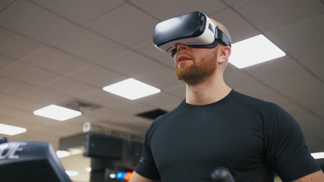 Junger-starker-Mann-trainiert-auf-Laufband-in-der-Turnhalle,-trägt-VR-Brille