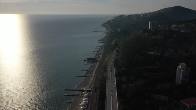 Aerial-video-shooting.-The-black-sea-coast-of-Sochi.-Road-along-the-coast.-Sunset-over-the-horizon.-Panorama-shooting.