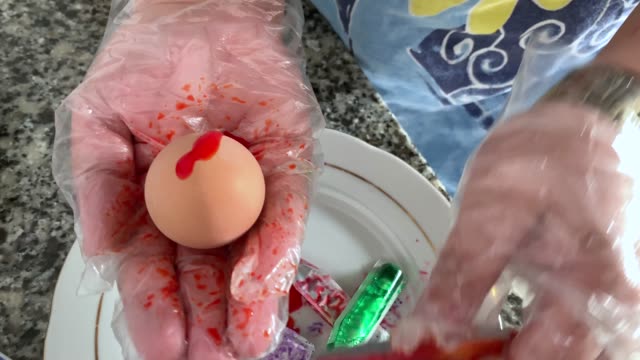 A-woman-in-gloves-paints-eggs