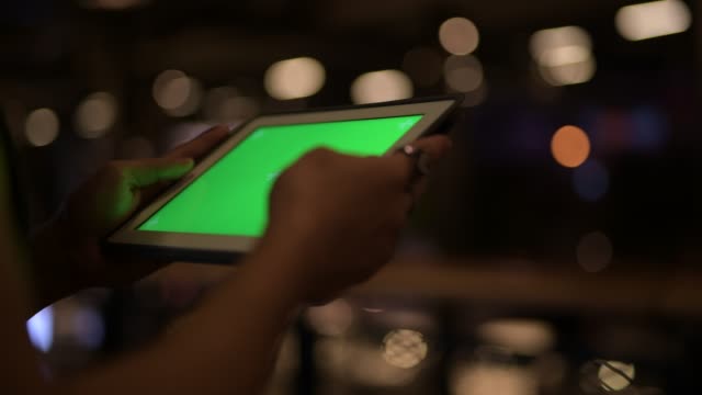 Manos-de-un-joven-asiático-usando-tableta-digital-por-la-noche