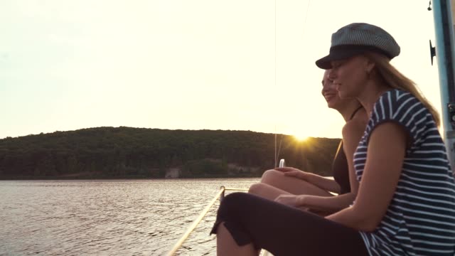 zwei-lesbische-Frauen-halten-Hände-auf-Segelboot-und-beobachten-Sonnenuntergang