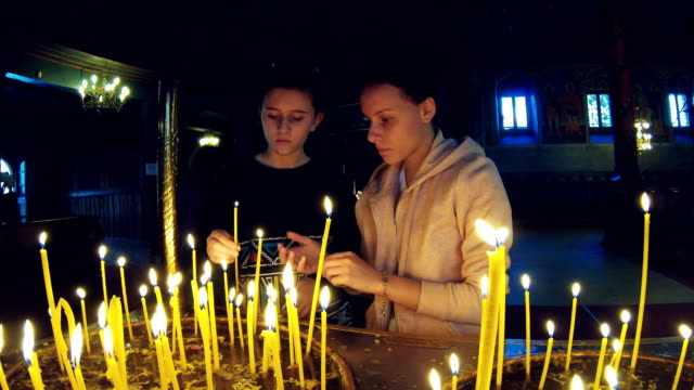 Zwei-Mädchen-zünden-Kerzen-an-und-beten-in-einer-großen-Kirche