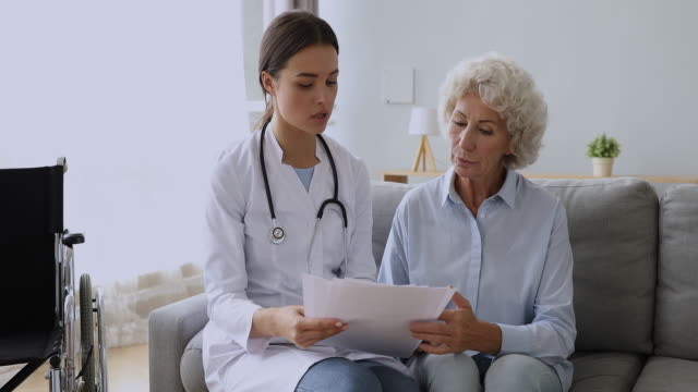 Junge-Ärztin-konsultieren-behinderte-alte-Oma-zeigen-medizinische-Testergebnisse