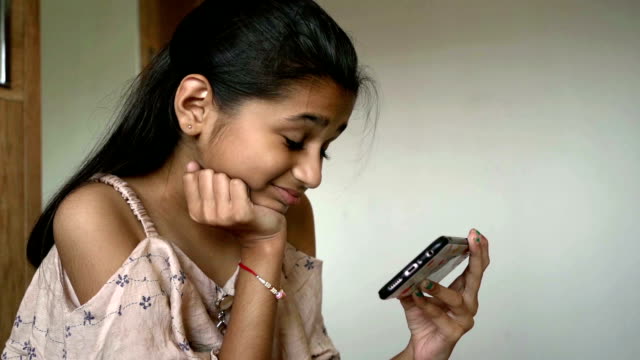 Niña-india-está-viendo-dibujos-animados-en-el-teléfono-inteligente-cámara-lenta