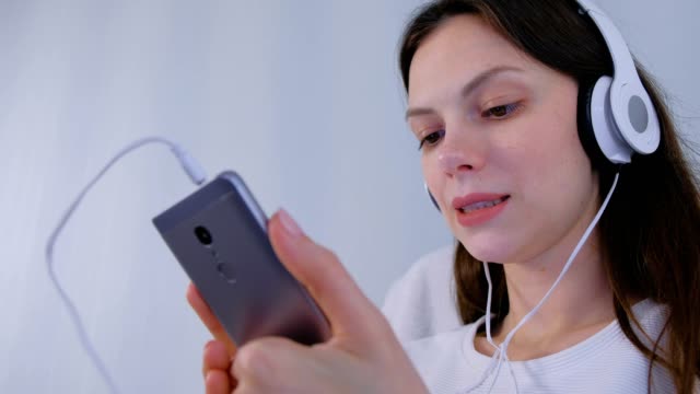 Frau-hört-Musik-in-Kopfhörern-auf-dem-Smartphone-und-singt-ein-Lied.
