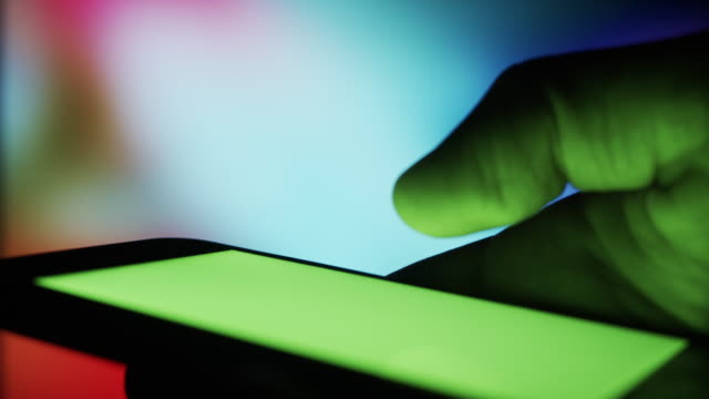 Smartphone-escote-por-la-noche---croma-clave-de-imagen-conceptual-de-pantalla-verde-con-fondo-colorido