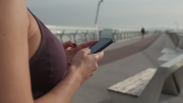 Sportlerin-mit-Smartphone-auf-Brücke.
