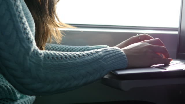 Female-hands-typing-on-keyboard-of-laptop-in-train.-Woman-chatting-with-friends-during-traveling-on-railway.-Young-girl-using-notebook.-Arm-print-a-message.-Close-up