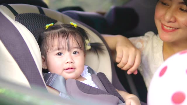 Schöne-asiatische-Mutter-Baby-im-Autositz-setzen