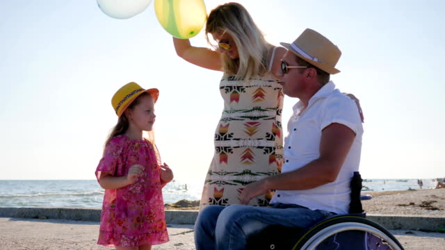 disabled-Man-In-wheelchair-with-child-consider-belly-of-pregnant-mom,-invalid-with-wife-and-daughter