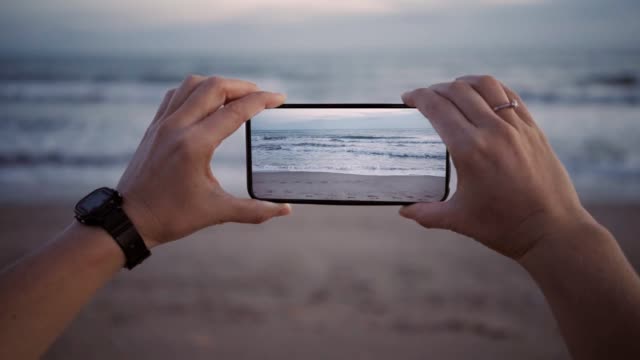 Rodaje-de-olas-en-la-playa-en-el-crepúsculo-en-nuevo-smartphone-con-pantalla-ancha