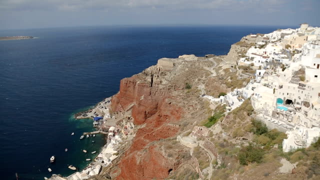 Casas-blancas-mentira-encima-Montaña-de-Santorini,-Bahía-en-la-parte-inferior-del-acantilado-rojo