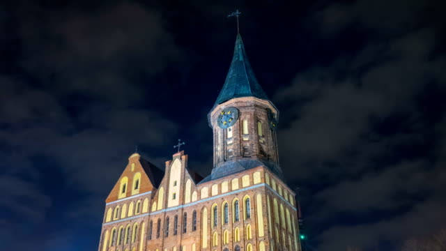 Illumination-on-a-historic-building.-Historic-Landmark.-Time-lapse.-Cathedral-of-Kant-in-Kaliningrad.-Old-medieval-castle-at-night-against-the-sky.-An-ancient-tower-with-a-clock.-Timelapse.