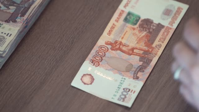 Weibliche-Hand-berührt-fünf-Tausend-Rubel-Banknote-auf-Tisch