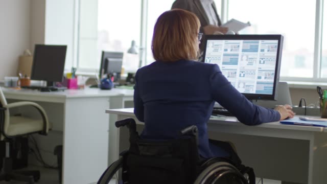 Mujer-en-silla-de-ruedas-con-colega-de-trabajo-en-oficina