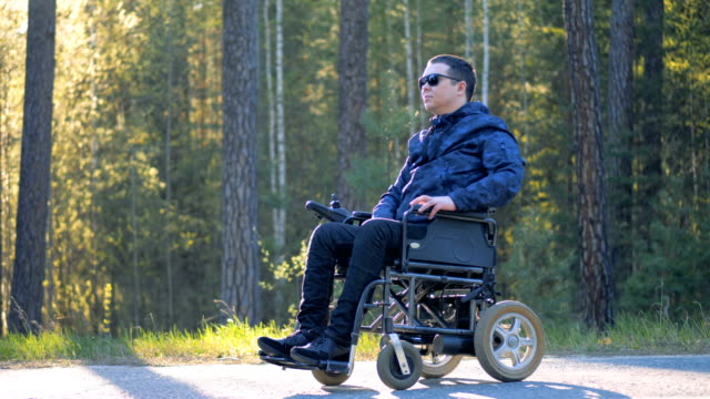 Un-hombre-en-silla-de-ruedas-mira-a-su-alrededor-en-un-bosque.