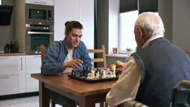 Fröhliche-junge-Mann-spielt-Schach-mit-Großvater